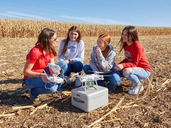 Instructor showing drone to students in field